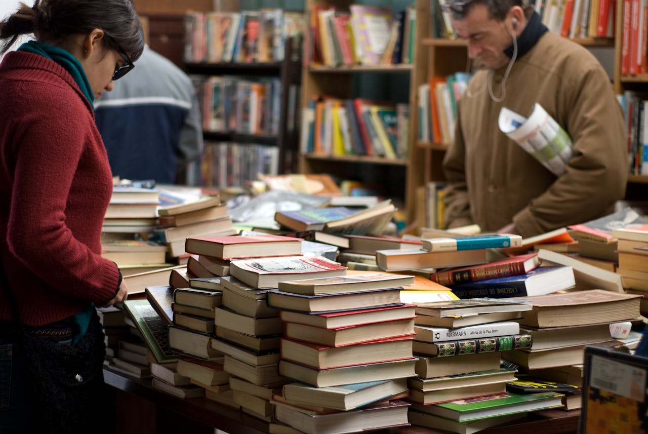 People browsing a large selection of books at a bookstore or market.